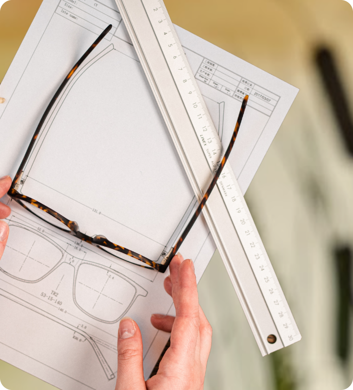 A person holding glasses and a ruler, measuring blue light absorption.